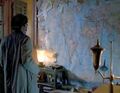 He locates a map, covered with pins and strings.
