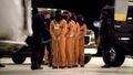 Team members guard the captives onto the plane.